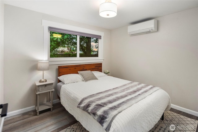 bedroom featuring wood finished floors, baseboards, and a wall unit AC