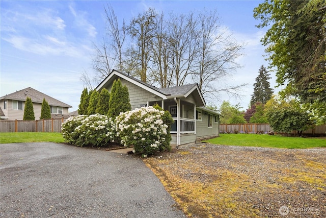 view of front of house with roof with shingles, a fenced backyard, and a front yard