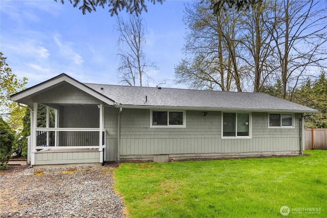 view of front of property featuring fence, a shingled roof, and a front lawn