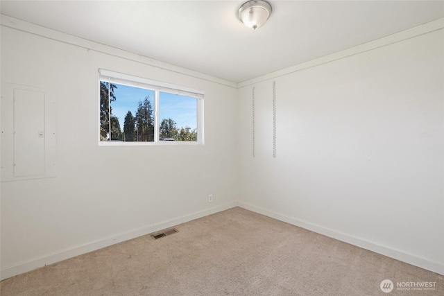 empty room with light colored carpet, baseboards, and electric panel