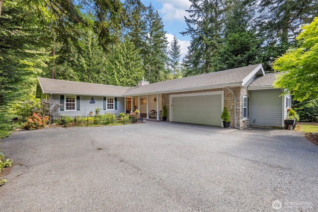 single story home featuring a chimney, a garage, aphalt driveway, and stone siding