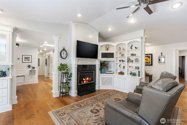 living area with a ceiling fan, light wood-style floors, lofted ceiling, and a fireplace