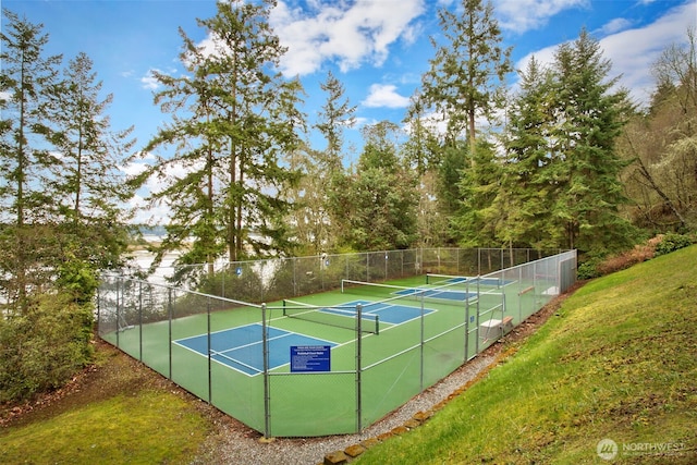 view of sport court featuring fence and a lawn