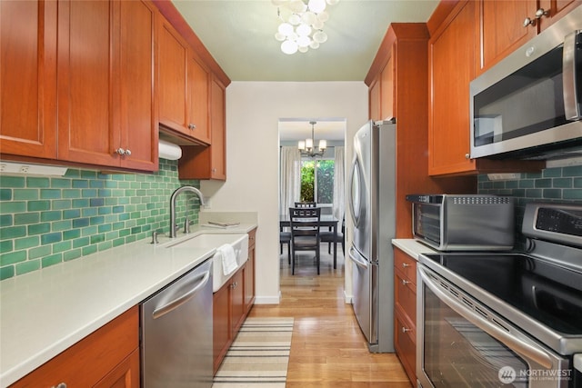 2858 32nd Ave W Unit 102, Seattle, WA 98199 - kitchen with brown cabinetry, a sink, a notable chandelier, and stainless steel appliances