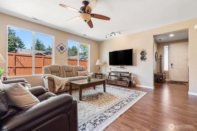 living area featuring a ceiling fan, visible vents, wood finished floors, and baseboards