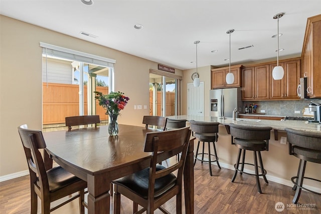 dining room featuring wood finished floors, visible vents, and baseboards