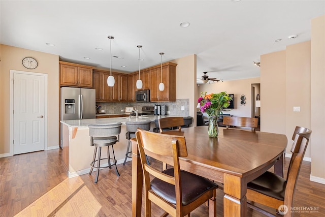 dining space with light wood finished floors, a ceiling fan, recessed lighting, and baseboards
