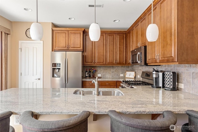 kitchen featuring visible vents, brown cabinets, appliances with stainless steel finishes, and a sink