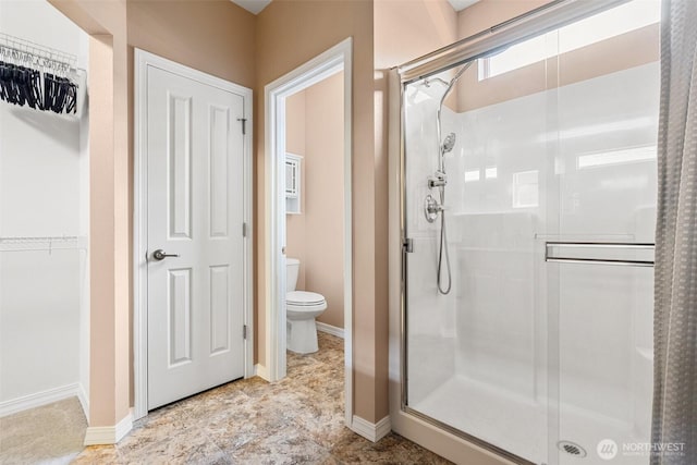 full bath featuring baseboards, a stall shower, and toilet
