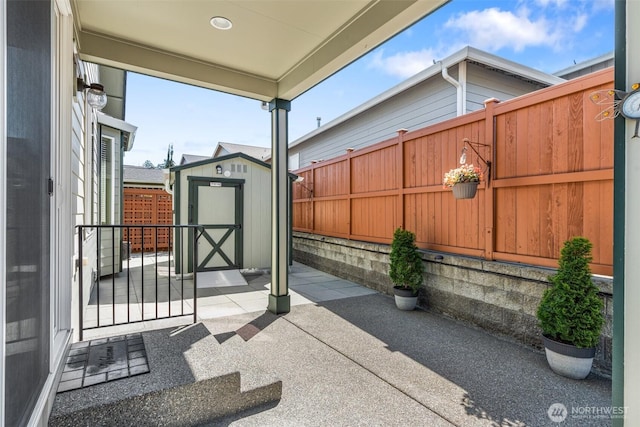 view of patio / terrace featuring an outbuilding, a storage shed, and fence