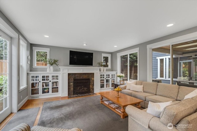 living area with wood finished floors, a fireplace, and recessed lighting