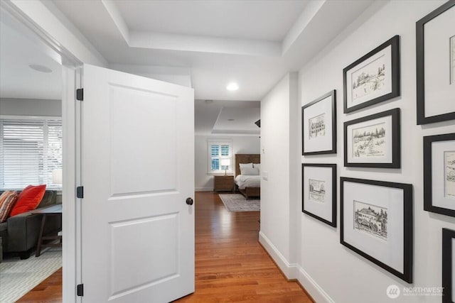 hallway featuring wood finished floors and baseboards