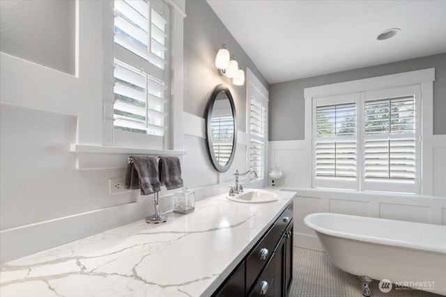 full bath with wainscoting, a soaking tub, and vanity