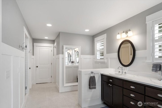 bathroom featuring wainscoting, walk in shower, vanity, and recessed lighting