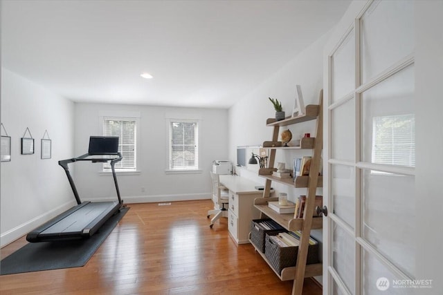 exercise room featuring baseboards, recessed lighting, and light wood-style floors