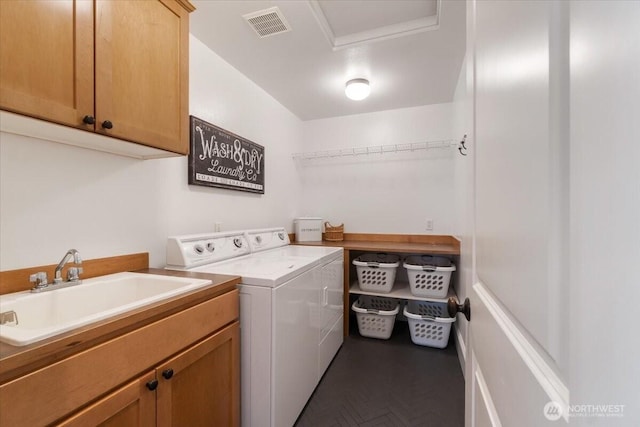 clothes washing area featuring washing machine and dryer, visible vents, a sink, and cabinet space