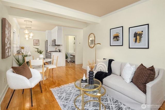 living area with a chandelier, light wood-style floors, baseboards, and ornamental molding