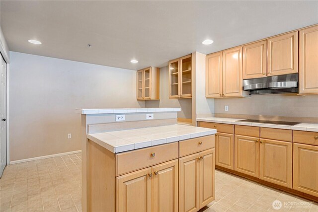 177 107th Ave NE Unit 1501, Bellevue, WA 98004 - kitchen with under cabinet range hood, tile counters, light brown cabinets, black electric stovetop, and glass insert cabinets