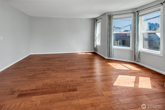 empty room with baseboards and dark wood-style flooring