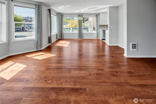 empty room with baseboards, heating unit, and dark wood-style floors