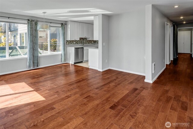 unfurnished living room with recessed lighting, baseboards, wood finished floors, and a sink