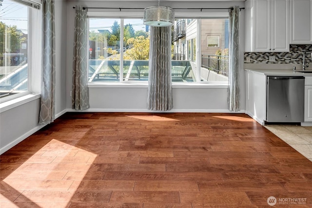 unfurnished dining area with baseboards, a sink, and light wood finished floors