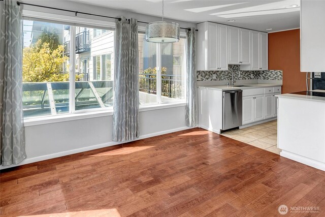 kitchen featuring plenty of natural light, stainless steel dishwasher, and light countertops