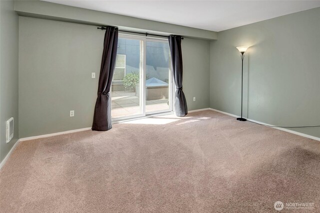 carpeted empty room featuring baseboards and visible vents