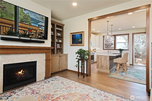 living room with recessed lighting, a tile fireplace, and light wood-style floors