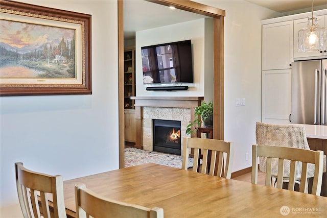 dining room featuring baseboards, a lit fireplace, and built in features