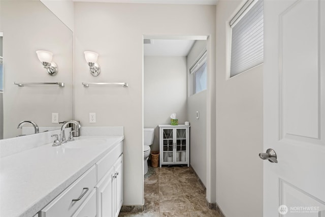 bathroom featuring baseboards, toilet, and vanity