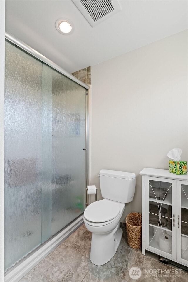 bathroom featuring visible vents, toilet, and a shower stall