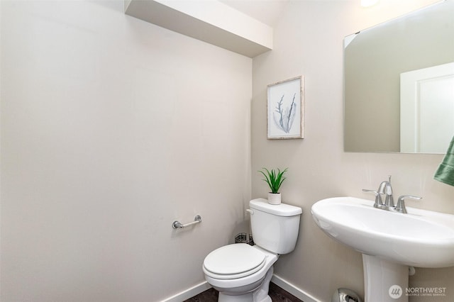 bathroom featuring baseboards, toilet, and a sink