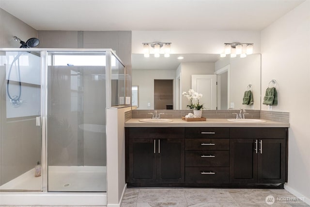 full bath with a stall shower, double vanity, and baseboards