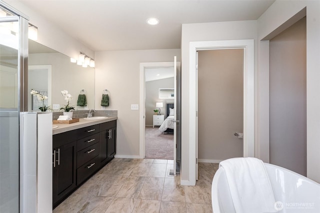 bathroom featuring a freestanding tub, double vanity, ensuite bathroom, recessed lighting, and baseboards