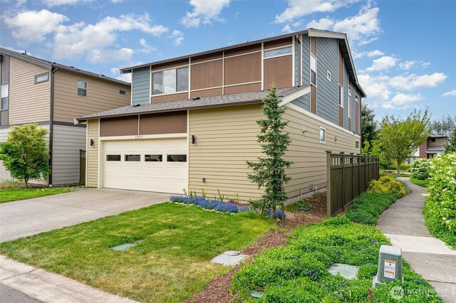 view of front of property featuring an attached garage, concrete driveway, fence, and a shingled roof