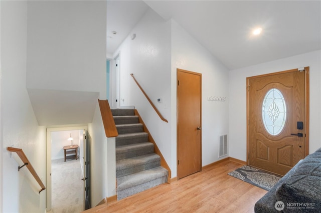 entryway with light wood-style flooring, lofted ceiling, and baseboards