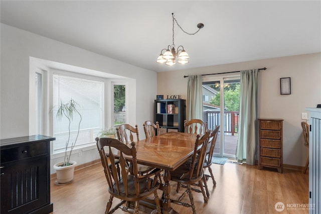 dining space with light wood-style floors, baseboards, and a chandelier