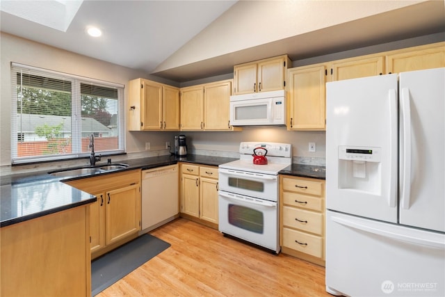 kitchen with white appliances, a sink, light brown cabinets, lofted ceiling, and dark countertops