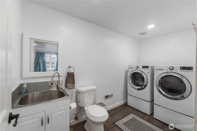 laundry room featuring washer and dryer, dark wood-style flooring, and baseboards