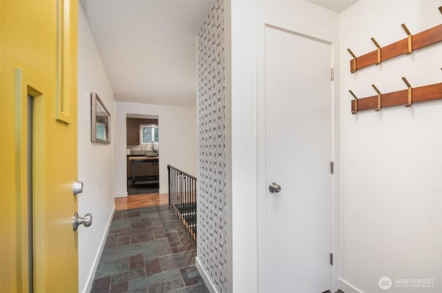 hall featuring stone finish floor and baseboards