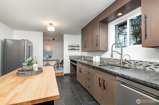 kitchen with dark tile patterned floors, a sink, butcher block counters, and stainless steel appliances