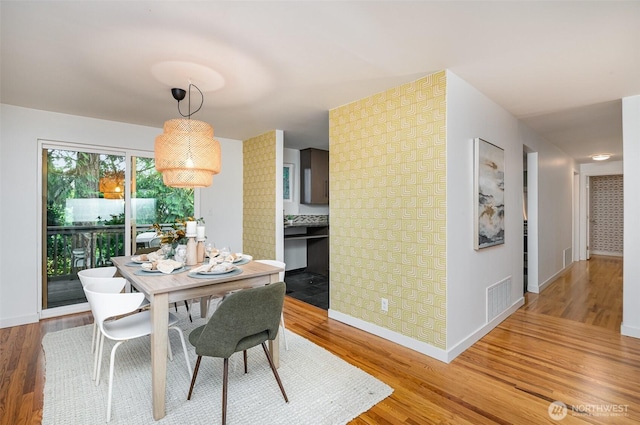 dining space featuring baseboards, wood finished floors, and visible vents