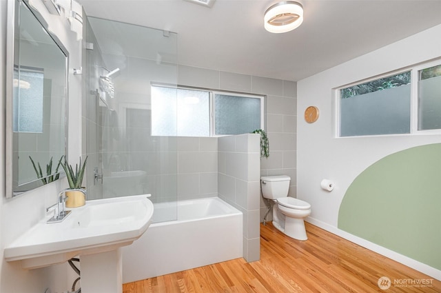 bathroom featuring tub / shower combination, toilet, plenty of natural light, and wood finished floors
