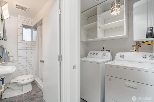 interior space featuring tankless water heater, laundry area, washing machine and dryer, and visible vents