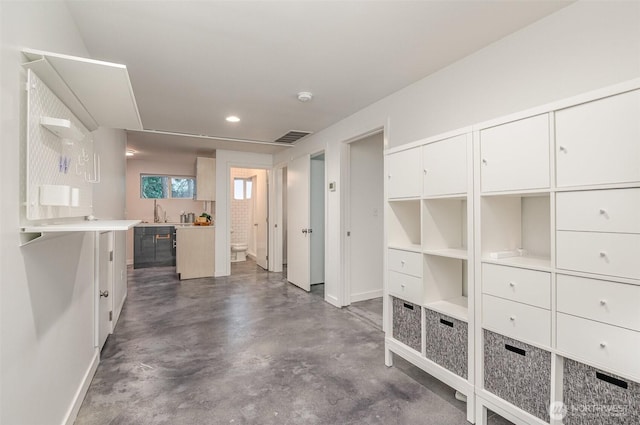 interior space with concrete flooring, a sink, recessed lighting, baseboards, and visible vents