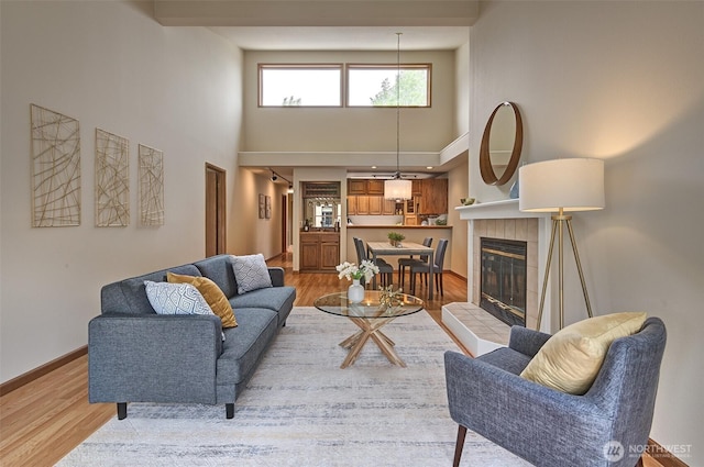 909 N 35th St Unit 402, Seattle, WA 98103 - living area featuring baseboards, a high ceiling, light wood-style flooring, and a fireplace