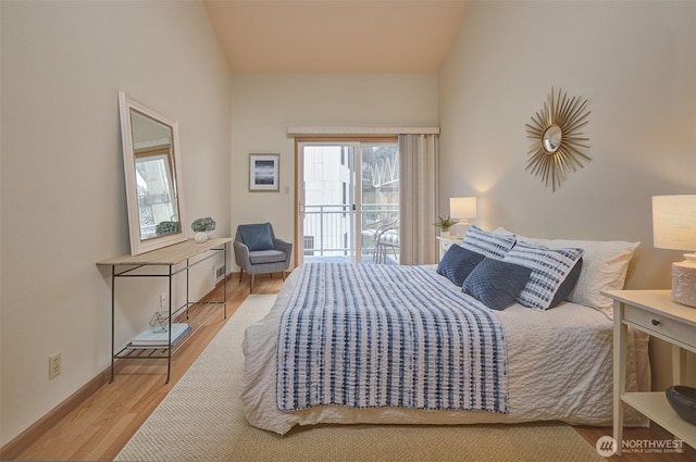 909 N 35th St Unit 402, Seattle, WA 98103 - bedroom featuring baseboards, vaulted ceiling, access to exterior, and wood finished floors