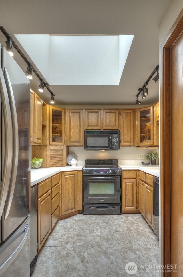 909 N 35th St Unit 402, Seattle, WA 98103 - kitchen with light countertops, rail lighting, a skylight, glass insert cabinets, and black appliances