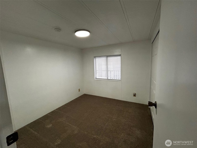 unfurnished room featuring dark carpet